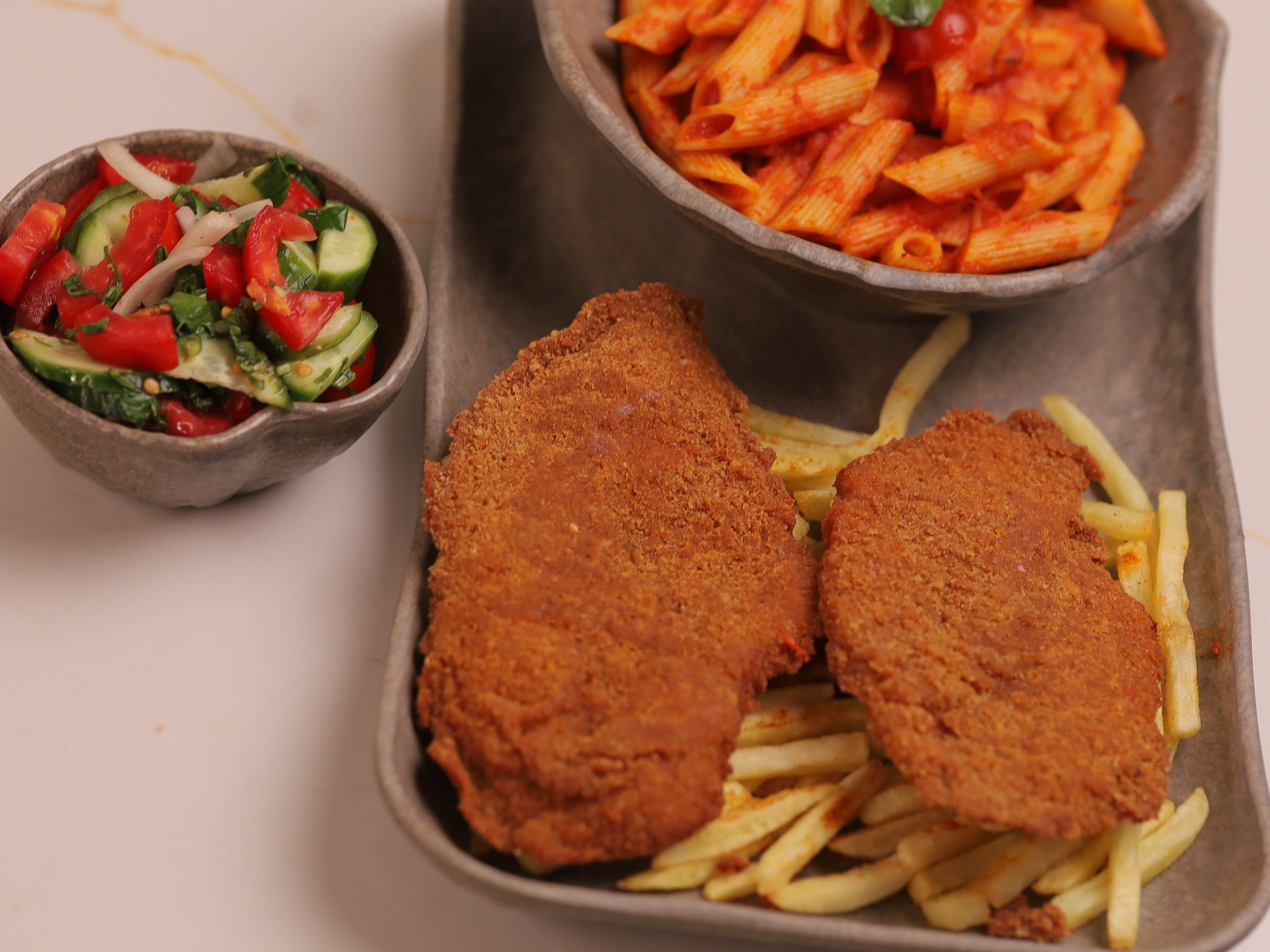 Breaded chicken with pasta, farm potatoes, and green salad