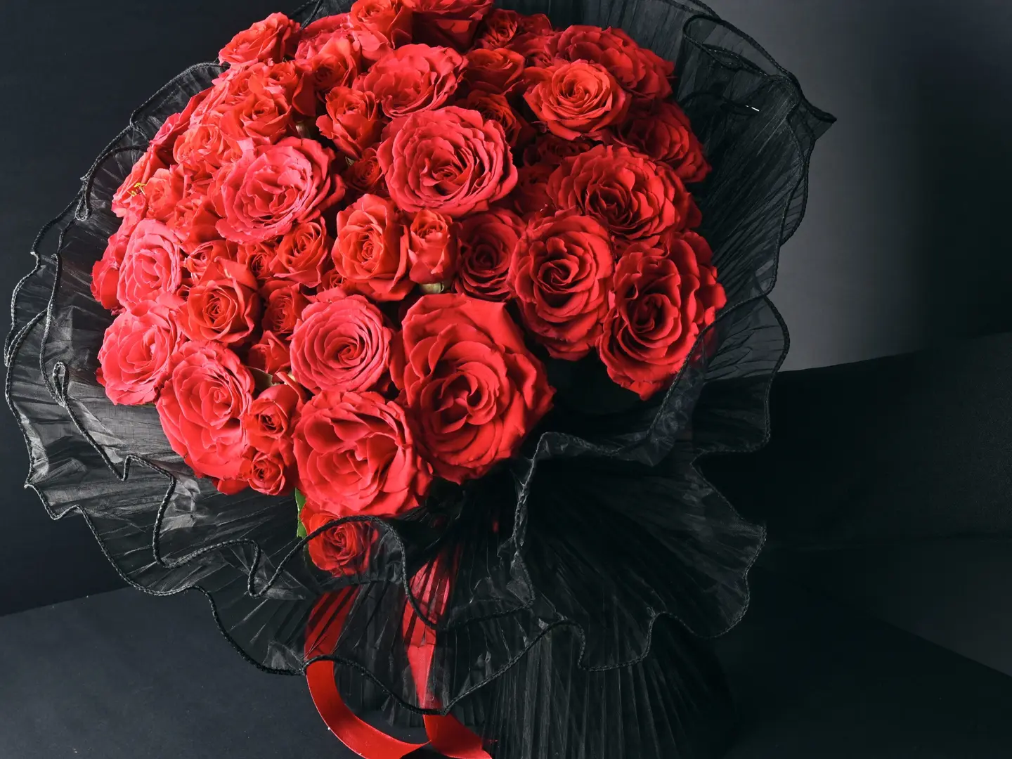 A Bouquet Of Red Roses In Black Fabric Wrapping