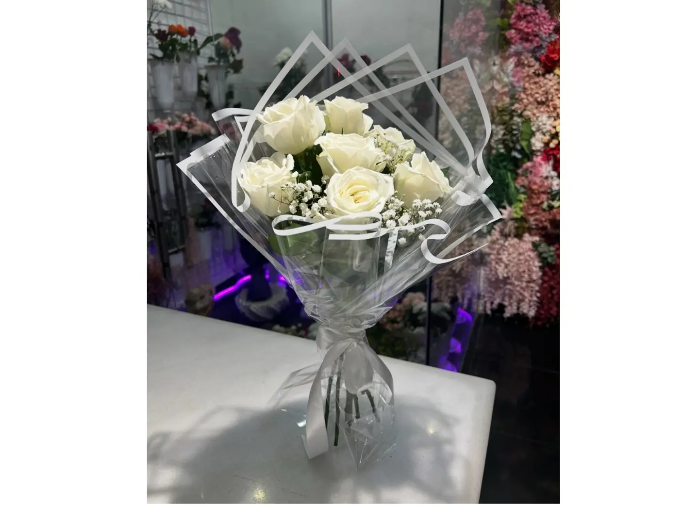 A Bouquet Of White Roses With Transparent Packaging