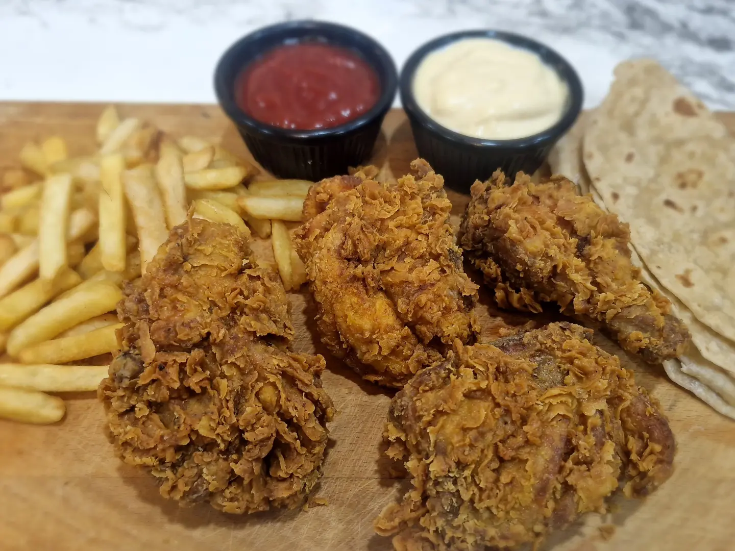 أربع قطع دجاج مشوي مع بطاطس مقلية وصلصة كاتشب وثوم حار