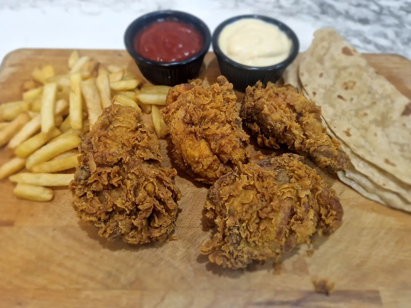 أربع قطع دجاج مشوي مع بطاطس مقلية وصلصة كاتشب وثوم حار