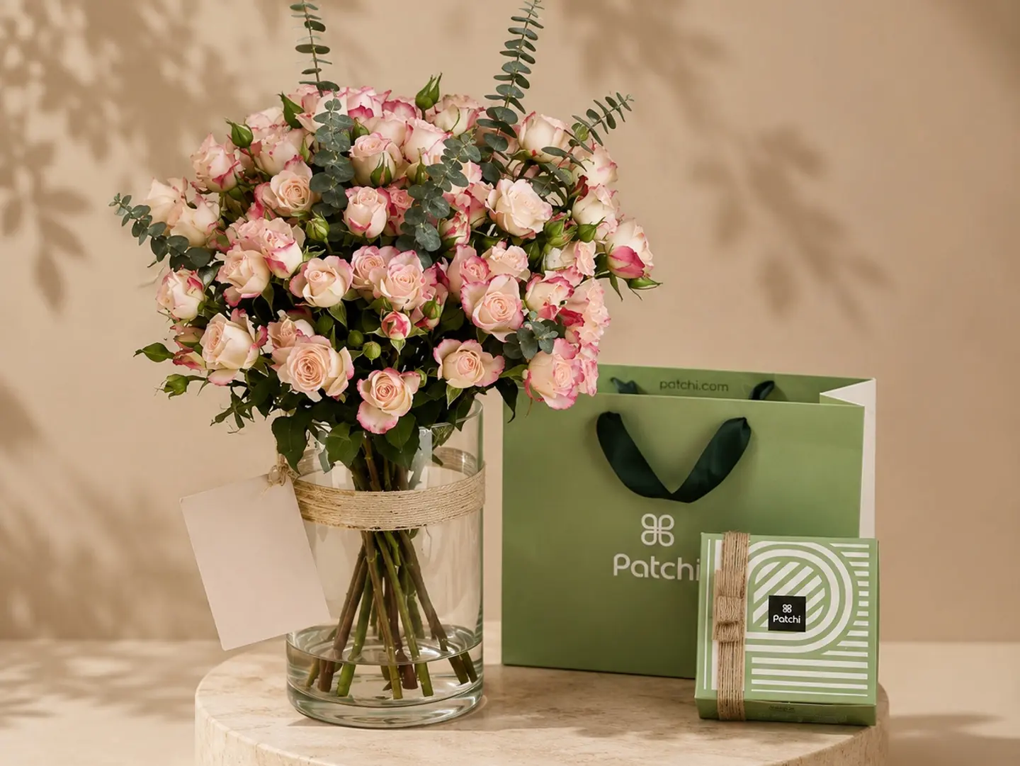 A Vase With White Flowers And Patchi Chocolates