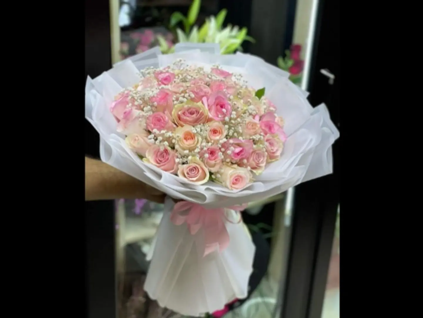 A Bouquet Of Pink Roses In White Packaging