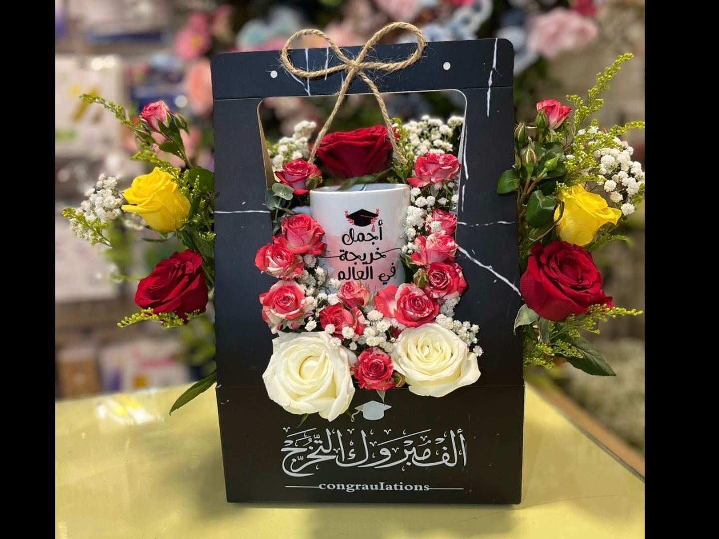 سلة كرتونيه اسود بعبارة الف مبروك التخرج مع كوب خريجه