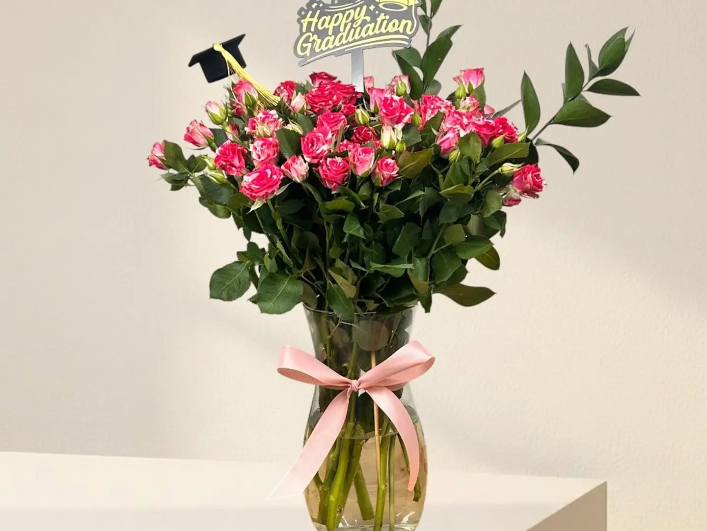 A Vase With Natural Baby Roses, Acrylic Toppers, And A Hat.