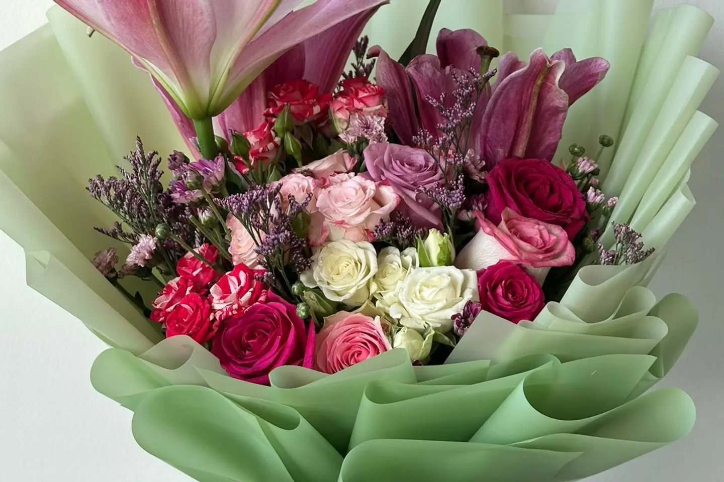 A Mixed Bouquet Of Roses Wrapped In Green