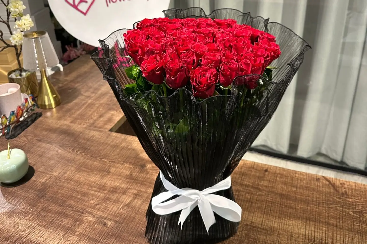 A Bouquet Of Red Roses And Black Packaging