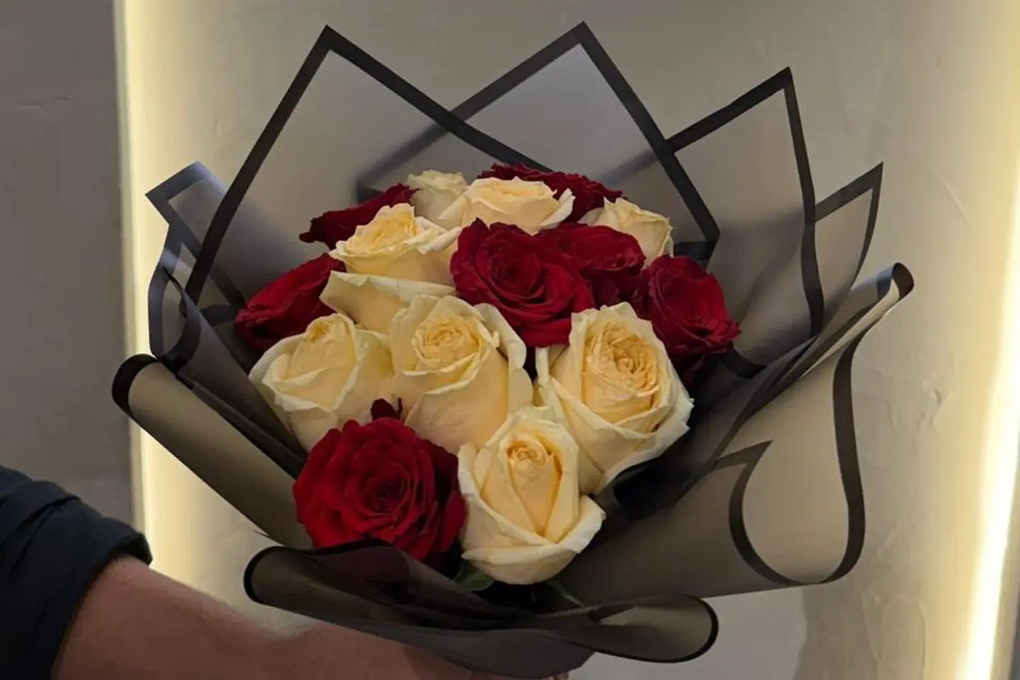 A Bouquet With Black Wrapping And Yellow And Red Roses