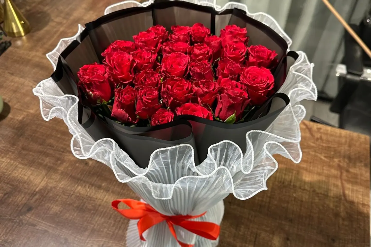 A Bouquet Of Red Roses In Black And White Packaging