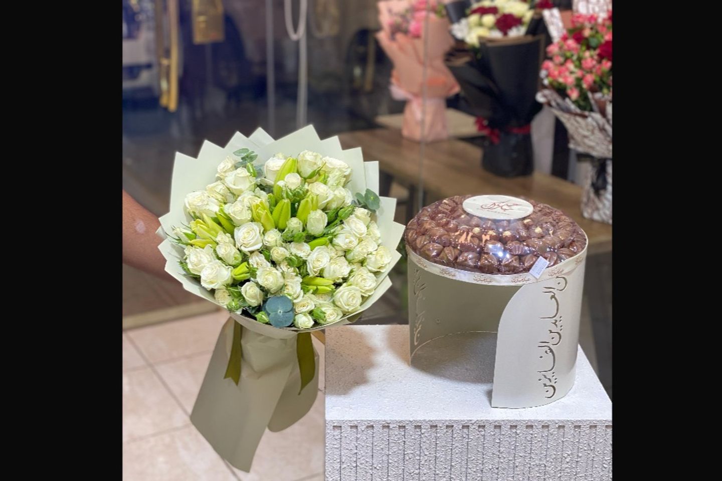 A Bouquet Of White Roses With A Tray Of Belgian Sweets