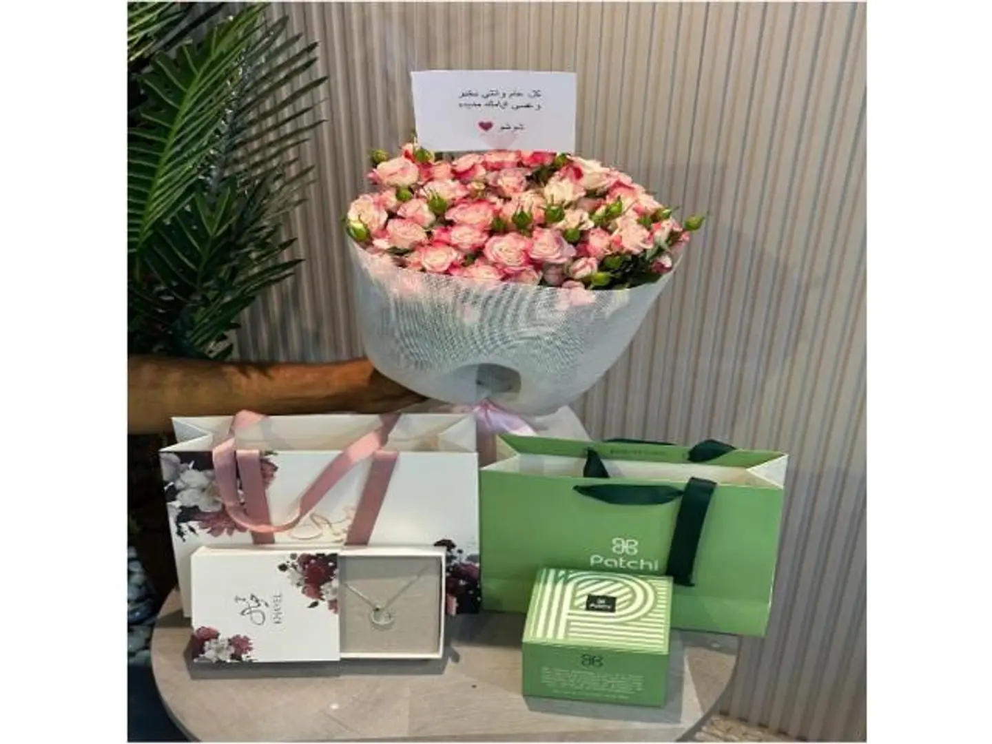 A Bouquet Of Roses With A Dream Necklace And Patchi Sweets