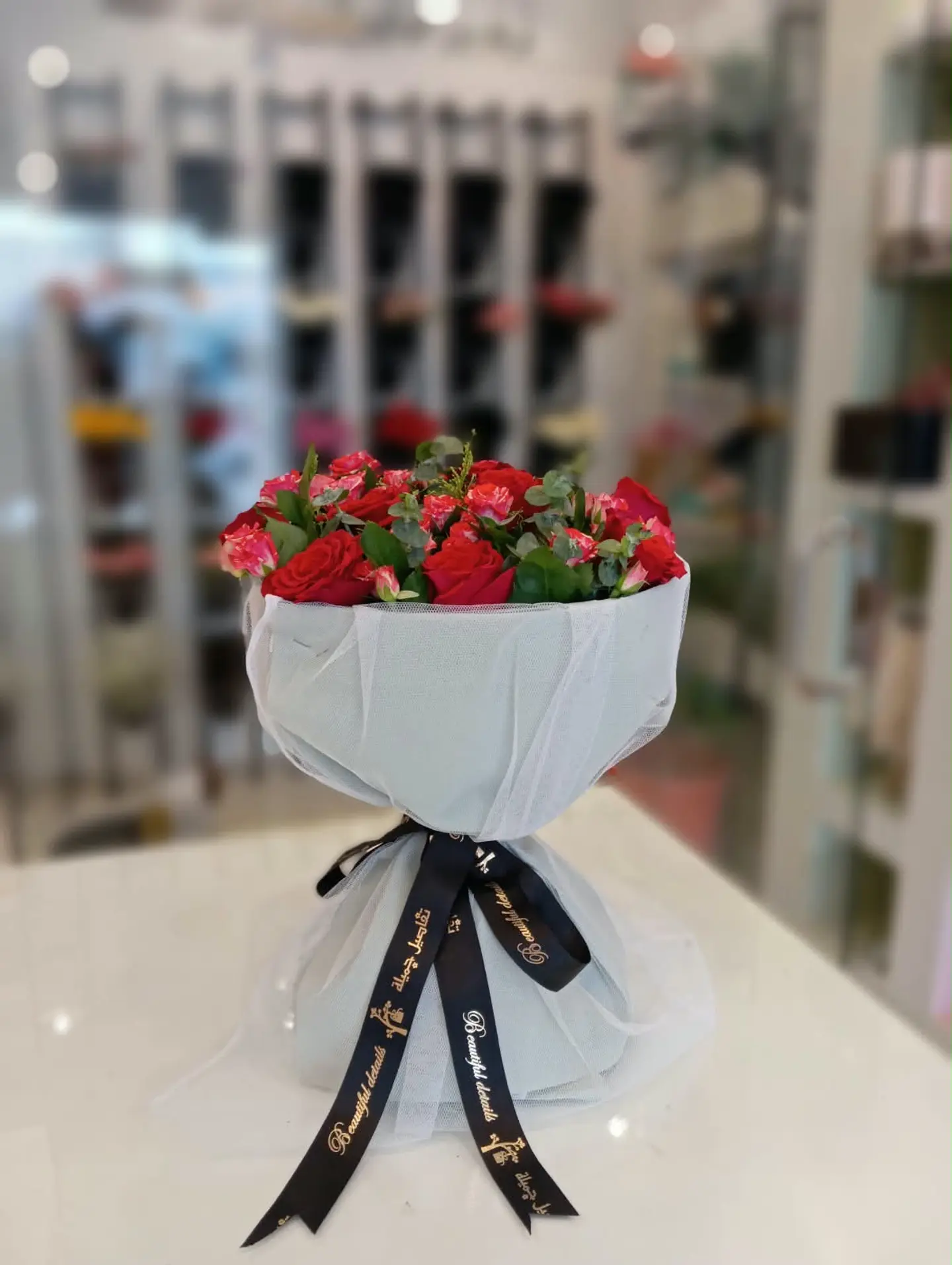 White Tulle Bouquet With Assorted Red Roses.