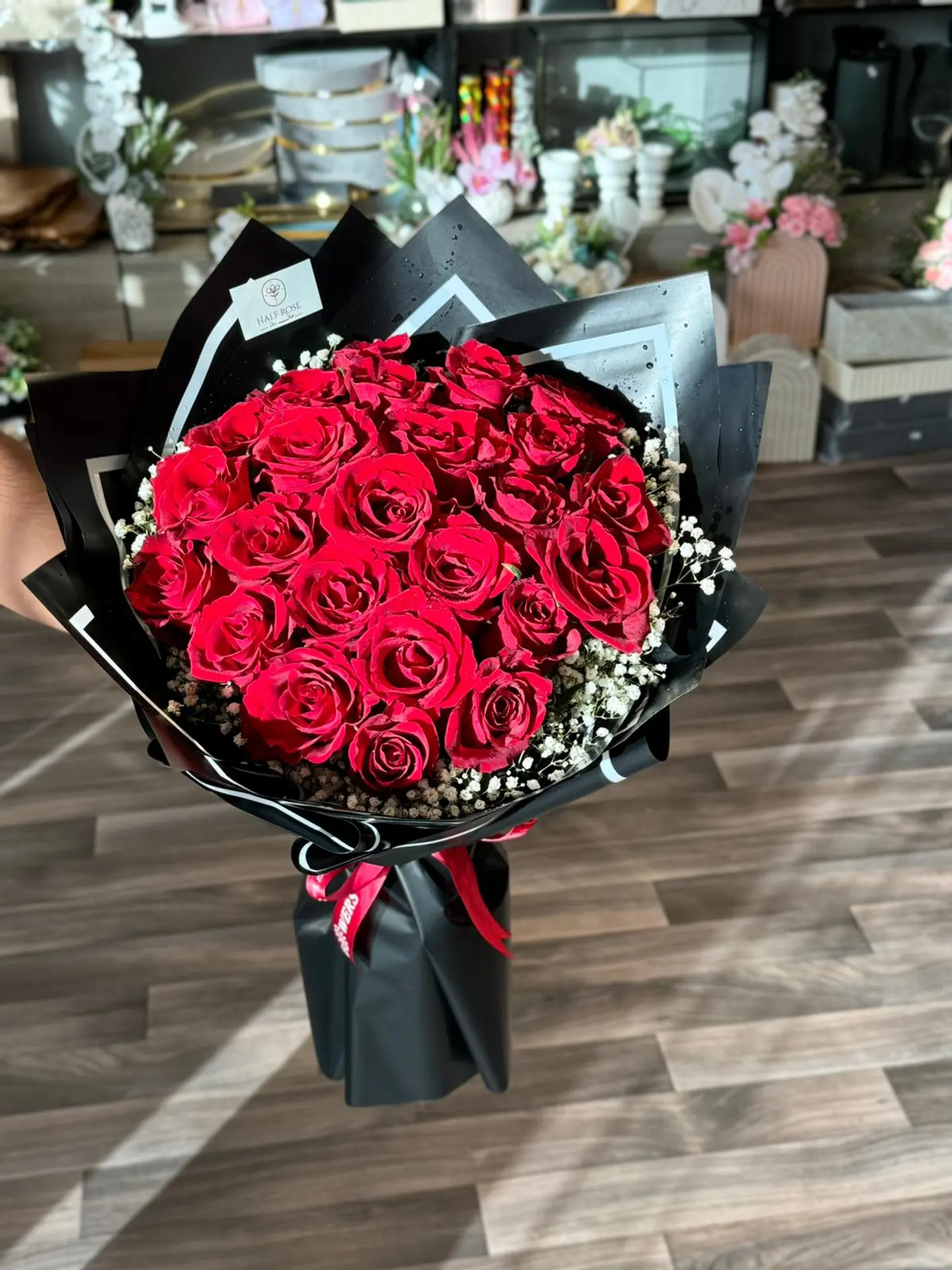 A Bouquet Of Red Flowers Wrapped In Black With A White Line.