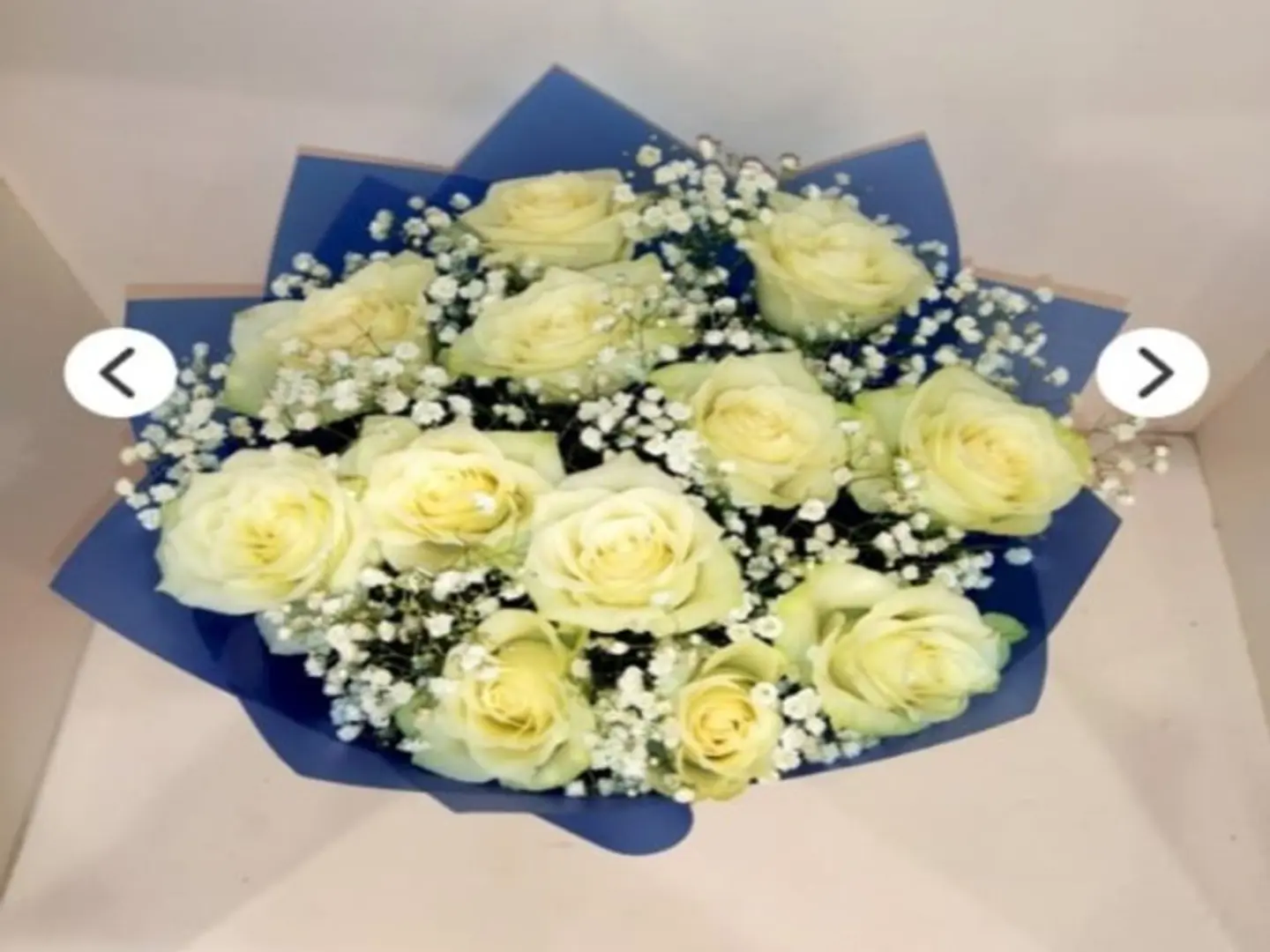 A Bouquet Of White Roses With A Blue Wrapper