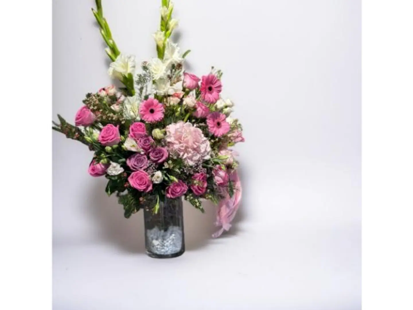 A Vase Of Small Flowers And Green Branches