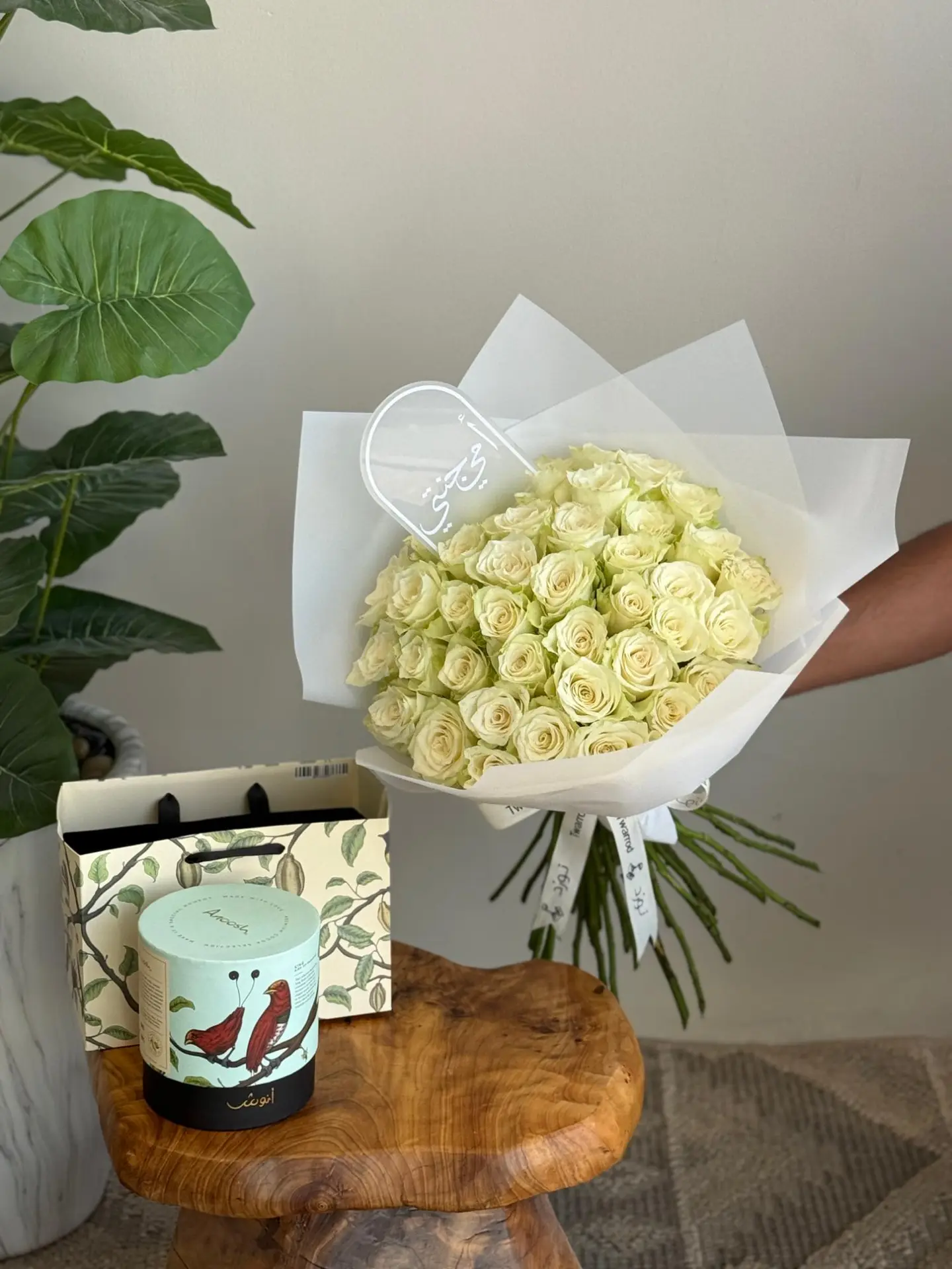A Bouquet Of White Roses With Chocolate And A Plant