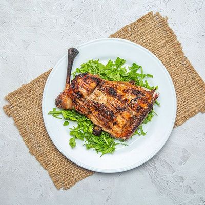 A quarter of grilled chicken thigh with bread and salad