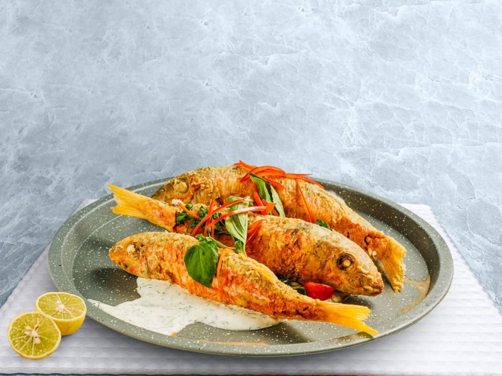Fried barbouni fish, sour cream, cherry tomatoes onion and parsley served with jasmin rice