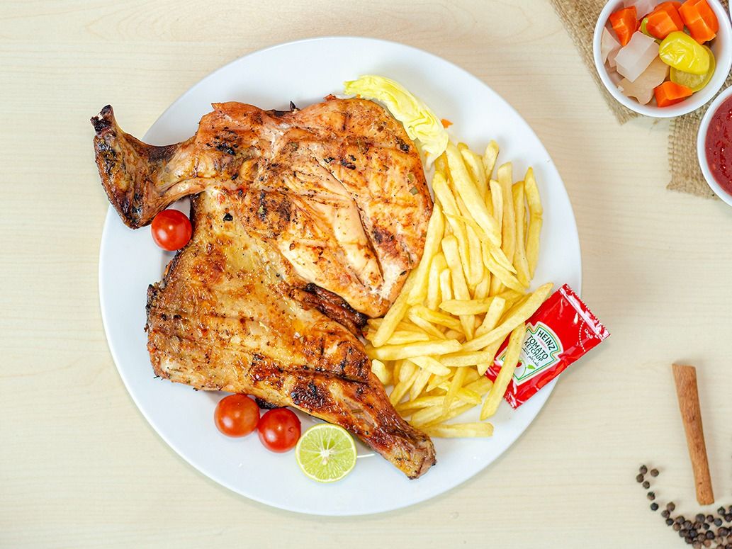 Half A Grilled Chicken With Potatoes And Bread